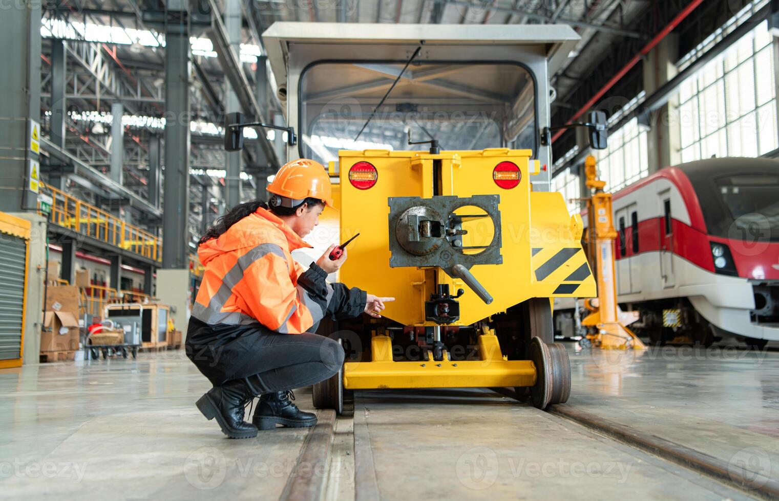 Female engineer working in electric train repair shop, Inspecting small grinding the railroad tracks machine before being put out for use. photo