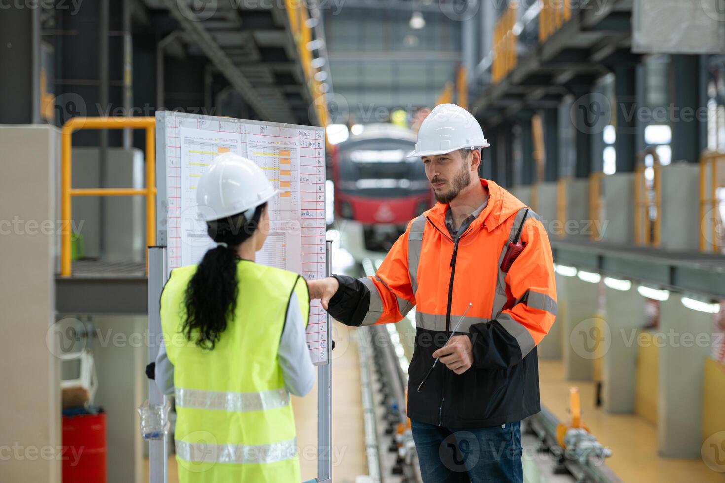 Male and female engineers work together in an electric repair station, Check the details of the electric train repair schedule. photo