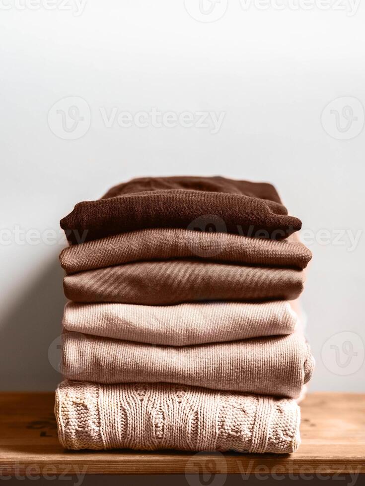 Pile of brown autumn clothes on wooden background, sweaters, knitwear, copy space photo