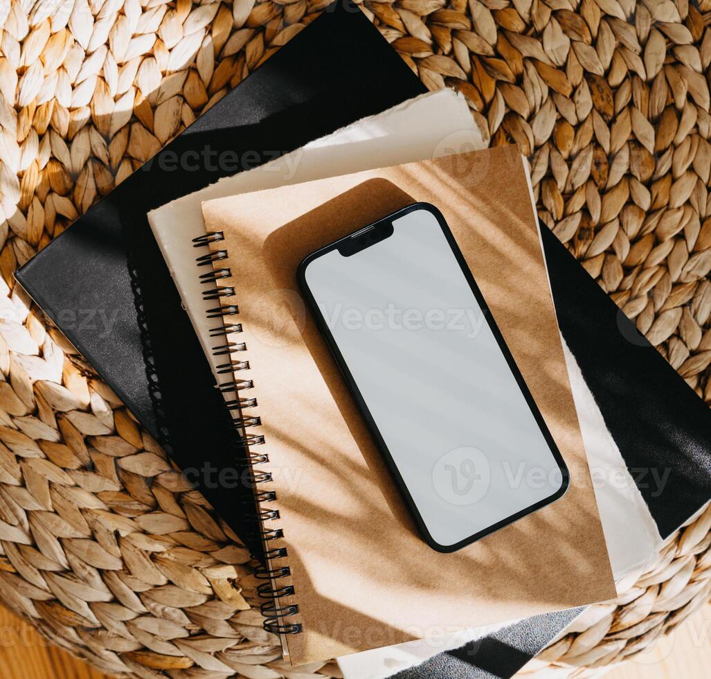 Blank path screen mobile phone with mockup on various notepads in sunlight with shadows photo