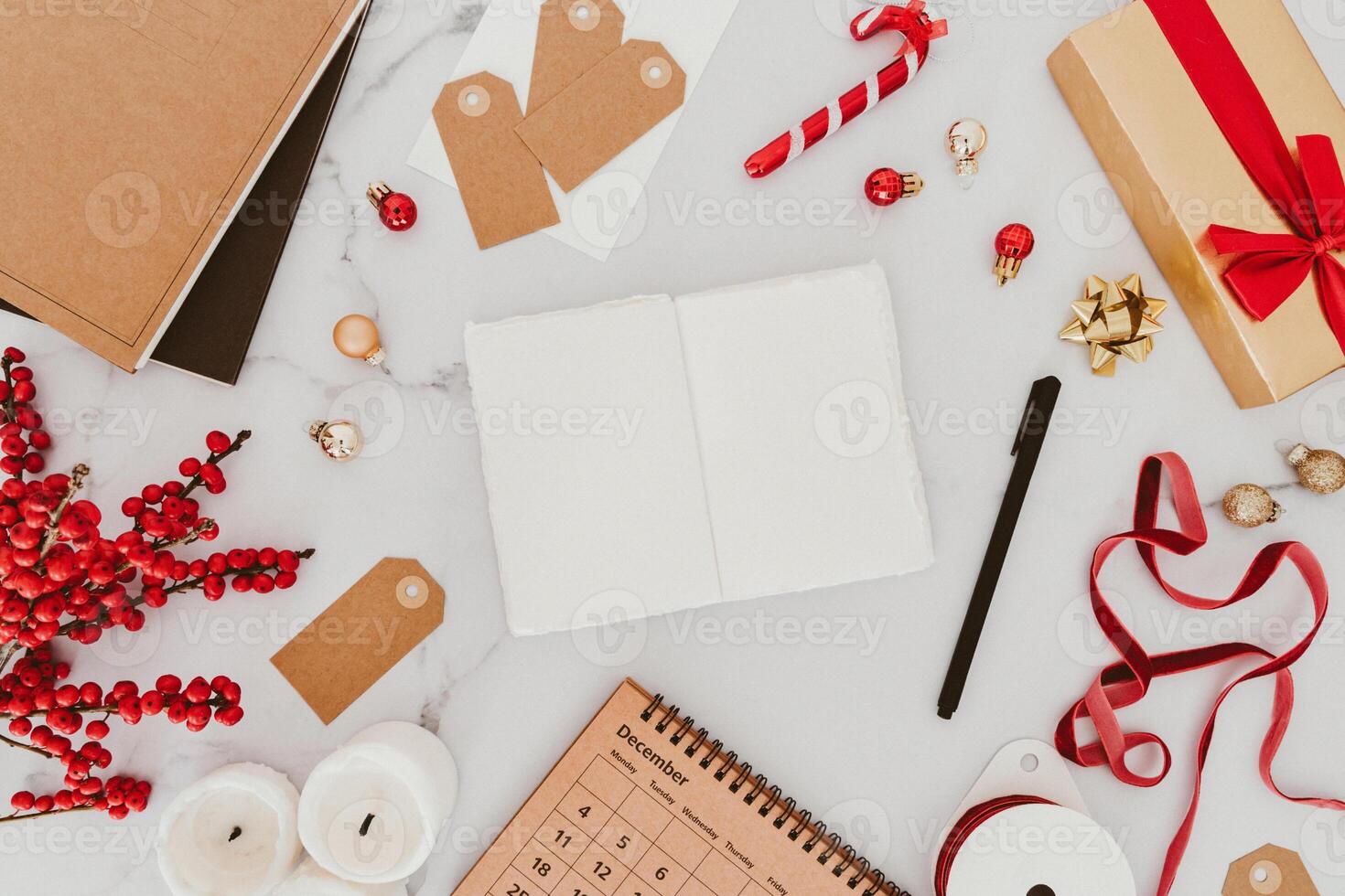 Christmas frame from decorations, gift package, candles and open blank notebook on white table background. photo