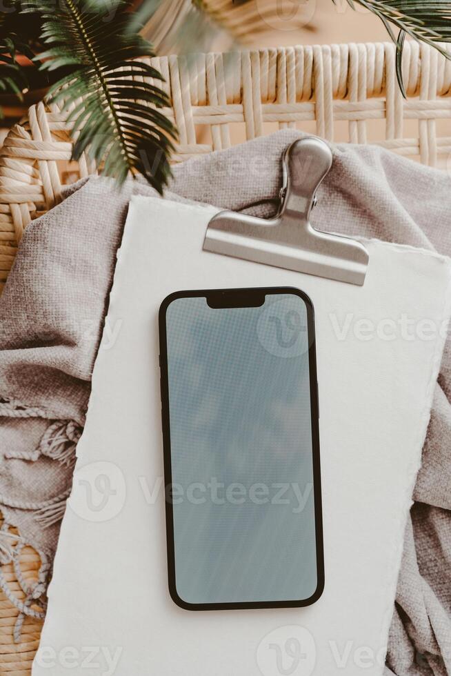 Blank path screen mobile phone with mockup on notepad, near green plant photo