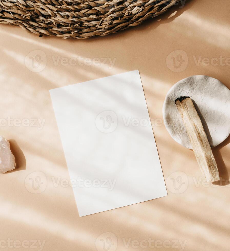 White blank card for text mockup, pink crystal and palo santo on beige background. photo