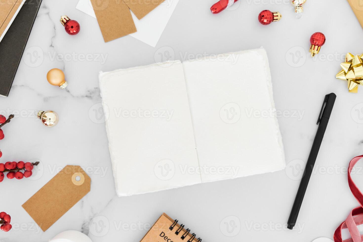 Christmas frame from decorations, gift package, candles and open blank notebook on white table background. photo