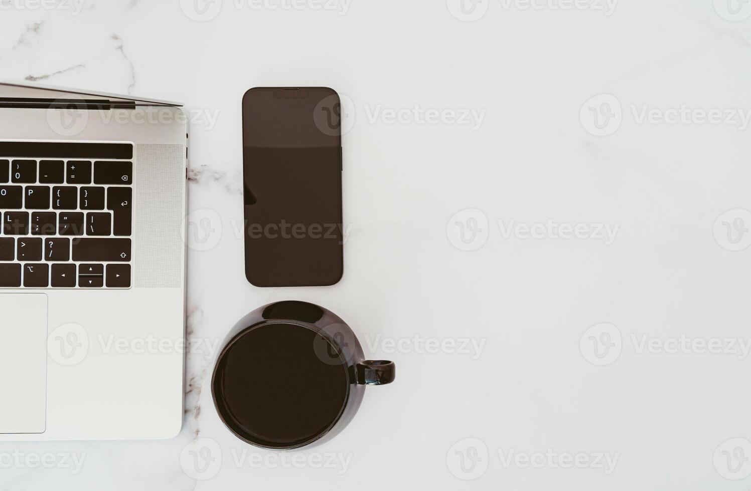 Minimal white office desk table with laptop computer, smartphone with black screen and cup of coffee photo