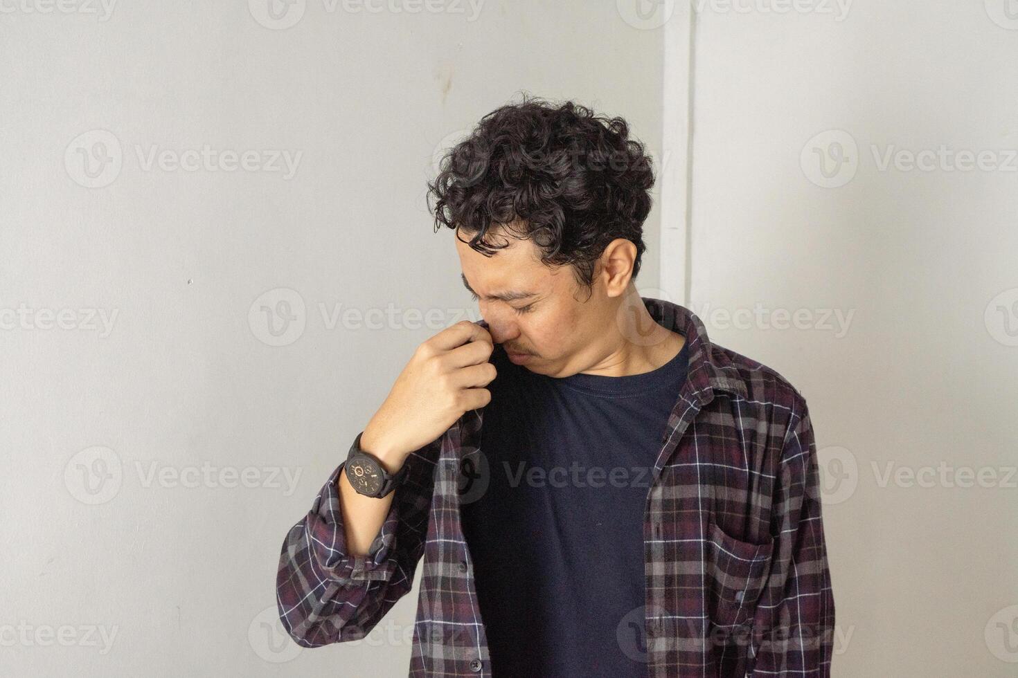 Asian man smells his bad odor armpit isolated on white background. photo