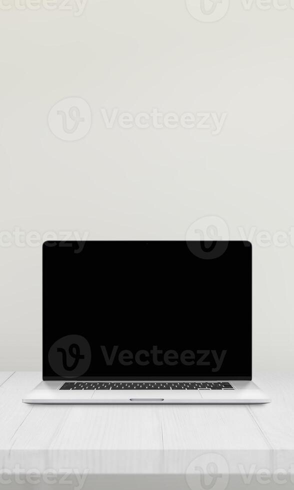 Laptop with a blank screen on a desk against a white wall, ideal for mockup presentations of websites photo