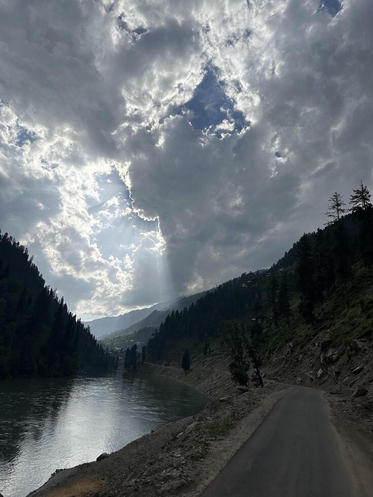 A road leading to a river with clouds in the sky photo