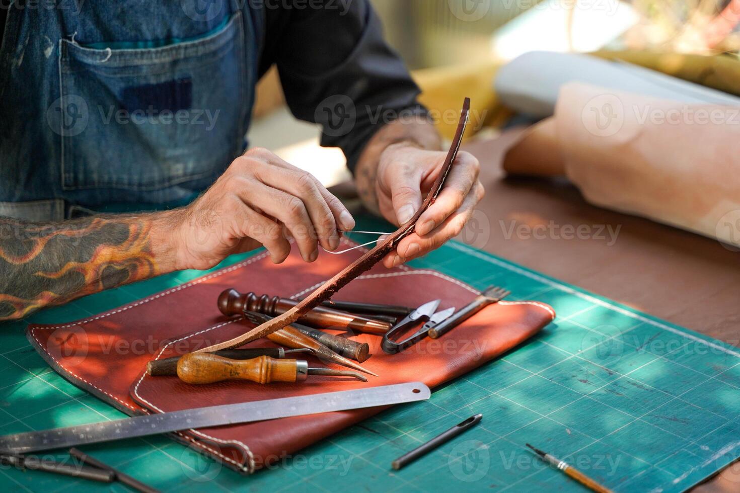 Closeup and crop hands of leather craftsman sewing and repair bag handle of leather brown bag for a customer in workshop. photo