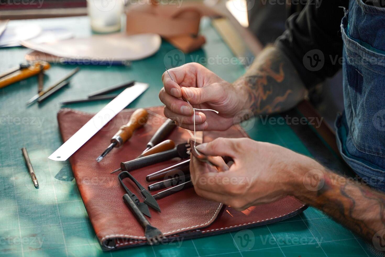 Closeup and crop hands of leather craftsman with his tool intend sewing and repair bag handle of leather brown bag for a customer in workshop. photo