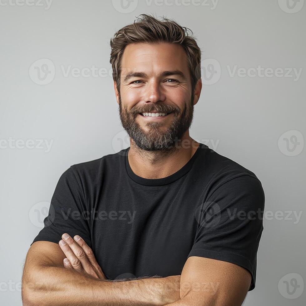 A headshot of a smiling, lights man with brown hair and a beard. The background is a plain gray. photo