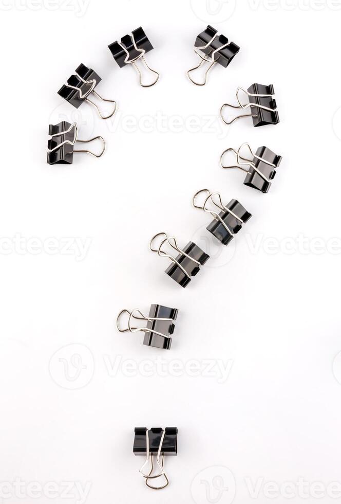 Black binder clips on a white background. Question mark of binder clips. photo