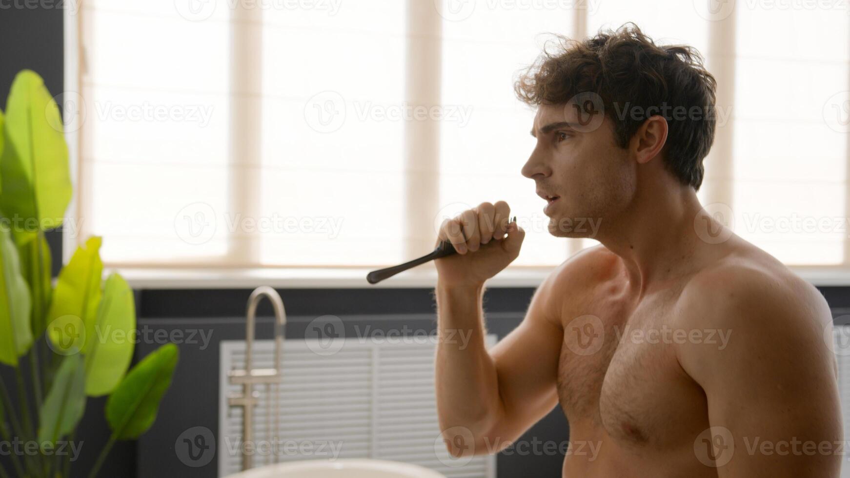 Close up funny naked humorous Caucasian man singing in comb throwing hairbrush in air happy guy carefree silly male dancing in bathroom looking at mirror dance in bath sing in hair brush having fun photo