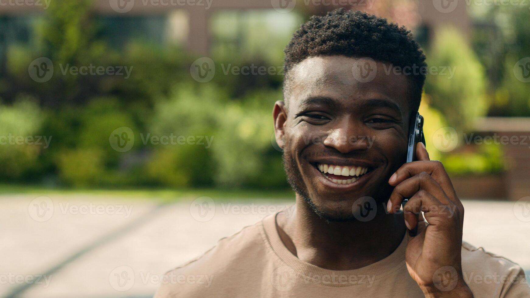African American happy laughing smiling joyful man ethnic talking mobile phone guy laugh smile walking in city answer call smartphone speaking outdoors male pleasant conversation friend cellphone talk photo