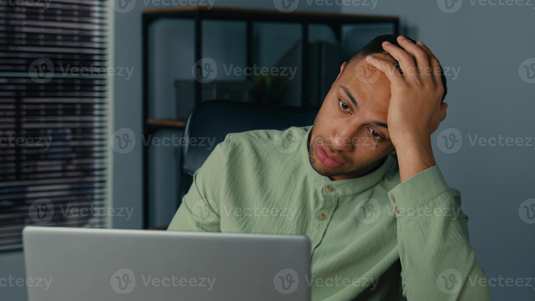 Desperate frustrated stressed african american man receive bad news by email on laptop in office evening sad worried shocked male businessman employee browsing computer crash error problem fail online photo