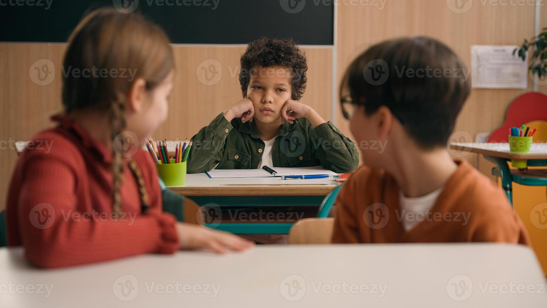 Multiracial diverse noisy little classmates multiethnic students pupils people children diversity kids friends noisy talking in school class at lesson sitting at table education learning studying talk photo