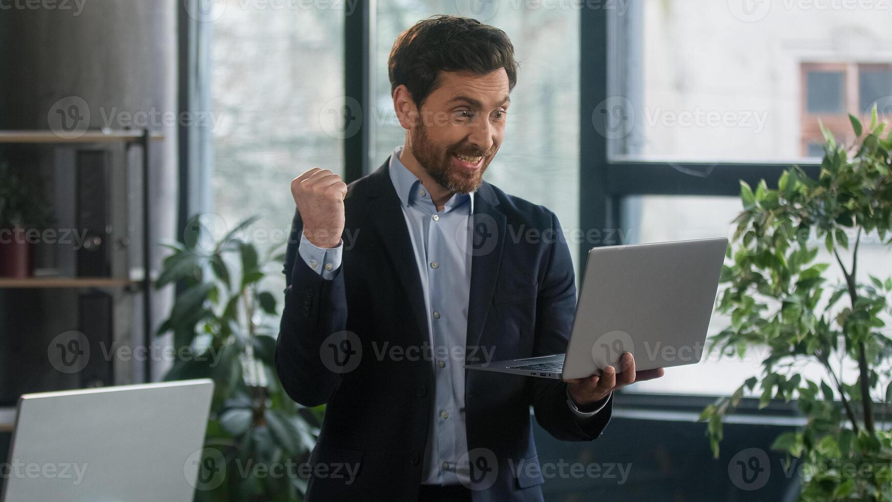 Happy excited businessman in office checking email on laptop read good news man winner successful entrepreneur receive reward bonus celebrating business success victory financial market growth concept photo