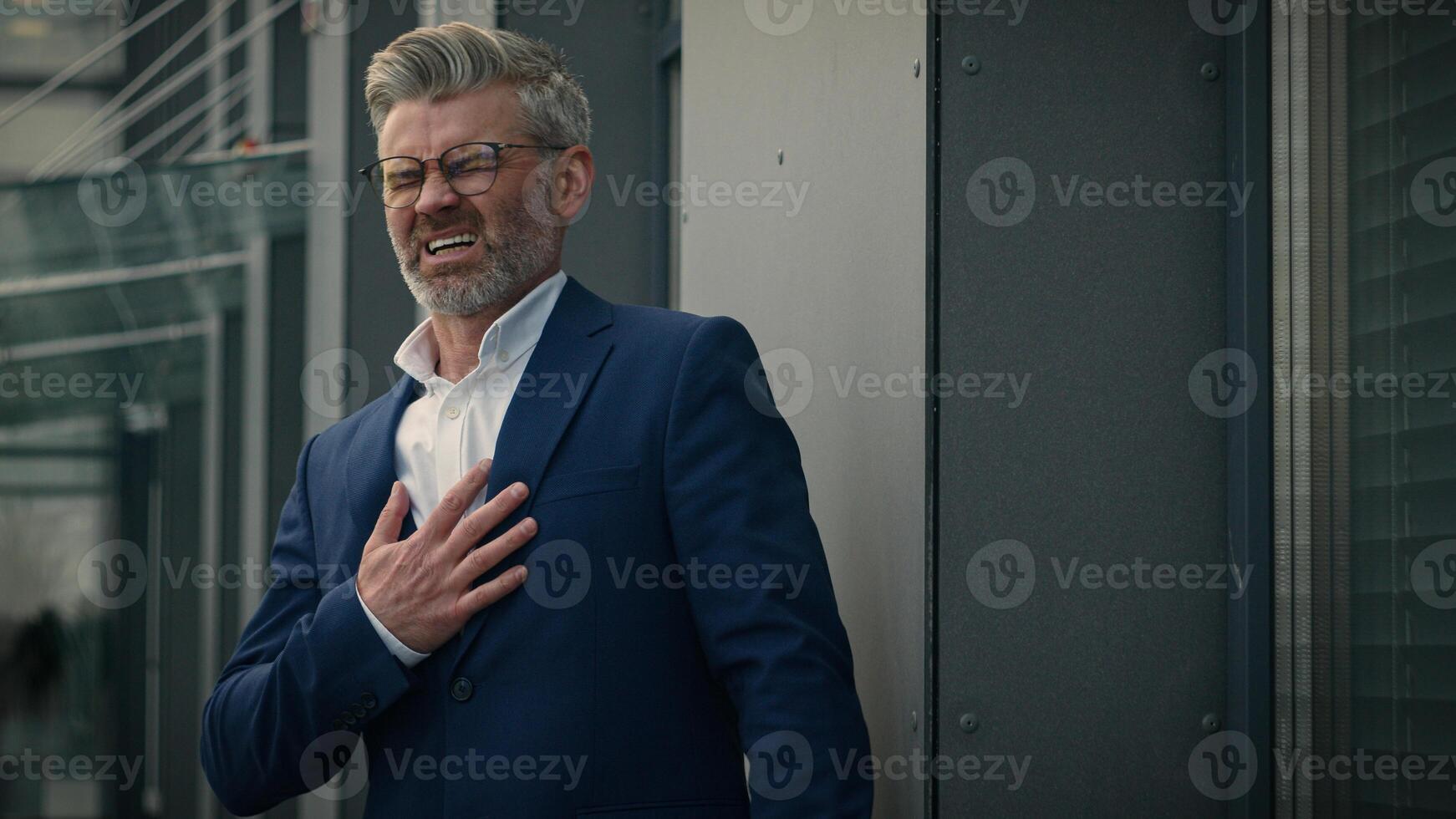 Middle-aged ill sick unwell unhealthy man mature businessman senior retired business employer in city near office building outdoors suffer heartache holding chest feeling pain symptom heart attack photo