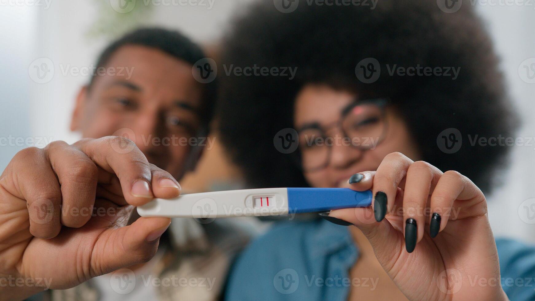 Portrait close up happy family spouses African American couple married man husband boyfriend with pregnant woman wife girlfriend showing camera holding positive pregnancy test future parents smiling photo