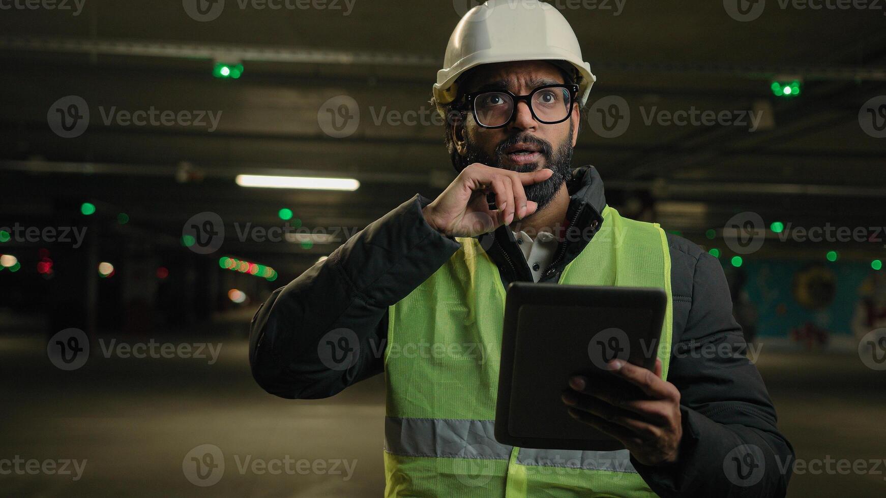Heavy industry technology engineer Arabian man Indian builder in hard hat electrician architect manufacture worker think pensive ponder problem solution use digital tablet check cyber security system photo