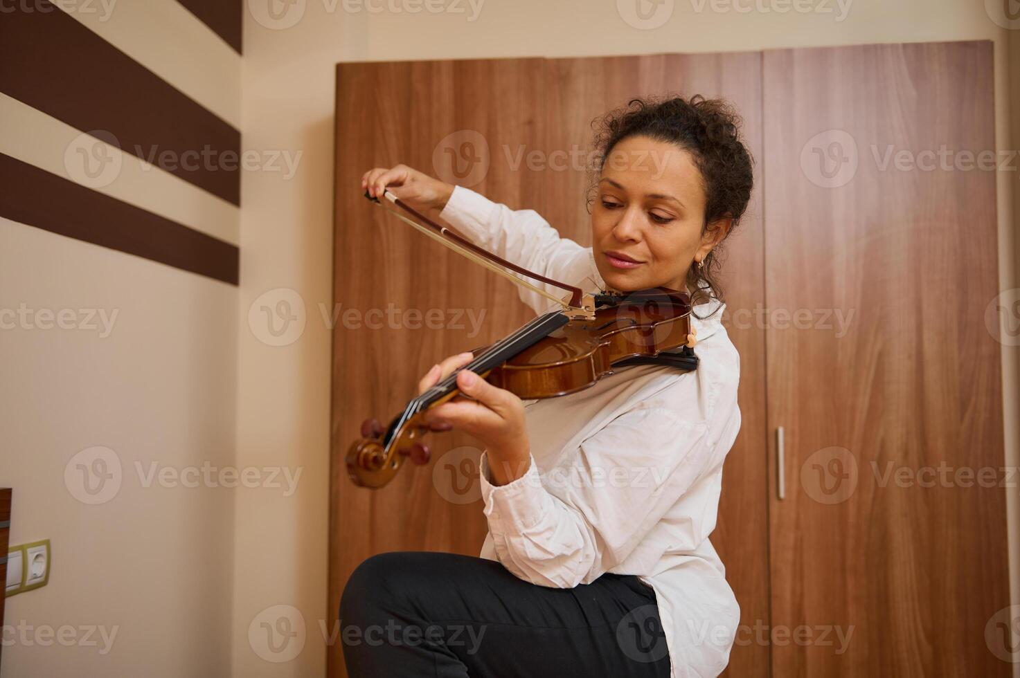 Woman practicing violin indoors, focusing on musical performance skills photo