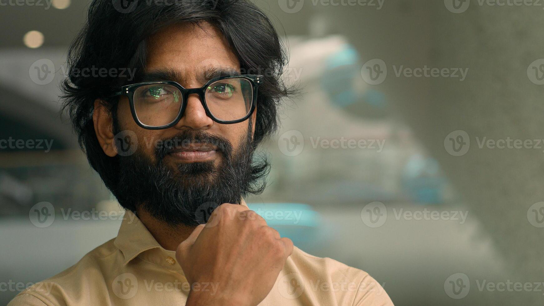 Thoughtful Arabian businessman looking away thinking of future business challenges. Doubtful serious pensive Indian bearded man in glasses entrepreneur lost in thoughts consider think smile to camera photo