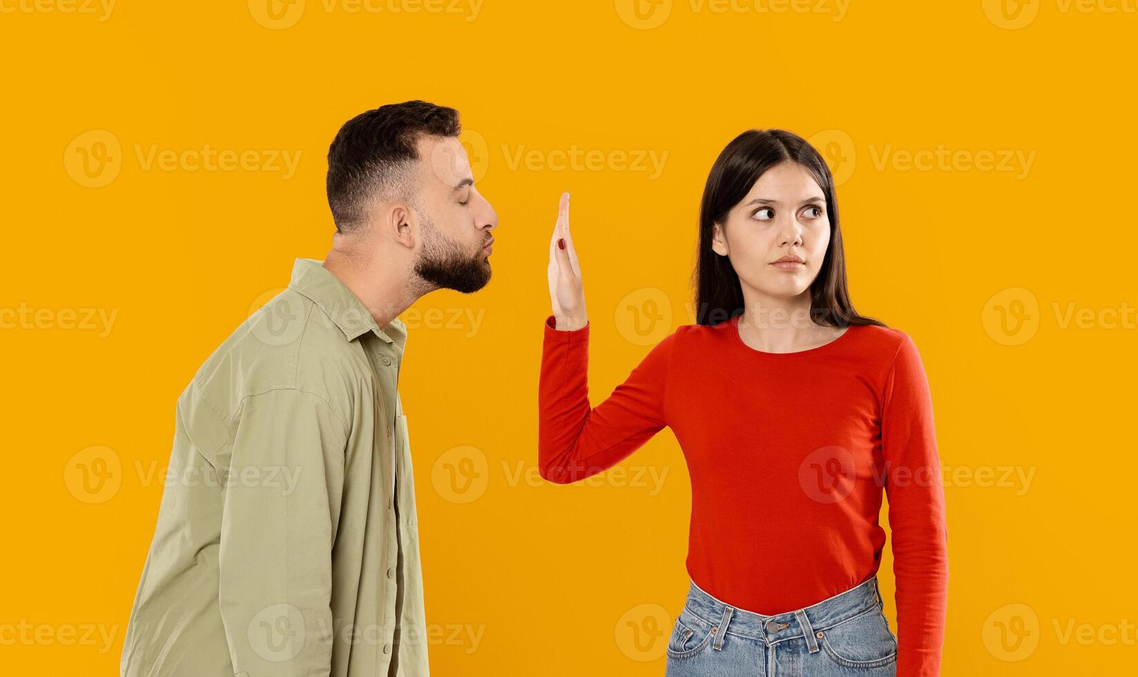 A young couple shares an affectionate moment but also experiences a disagreement. The man leans in close, while the woman raises a hand in a playful yet firm gesture. photo
