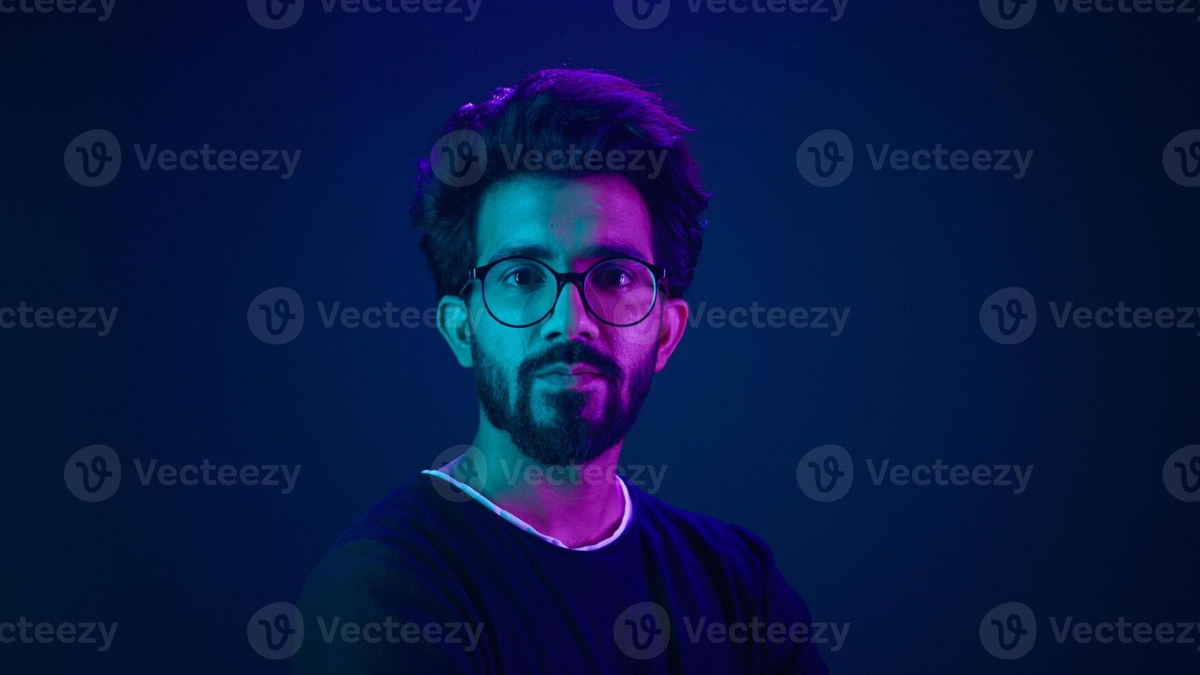 Portrait Indian serious man developer coding worker programmer profile looking to side turn head internet technology hacker male in glasses in blue ultraviolet studio background high-tech cyberspace photo