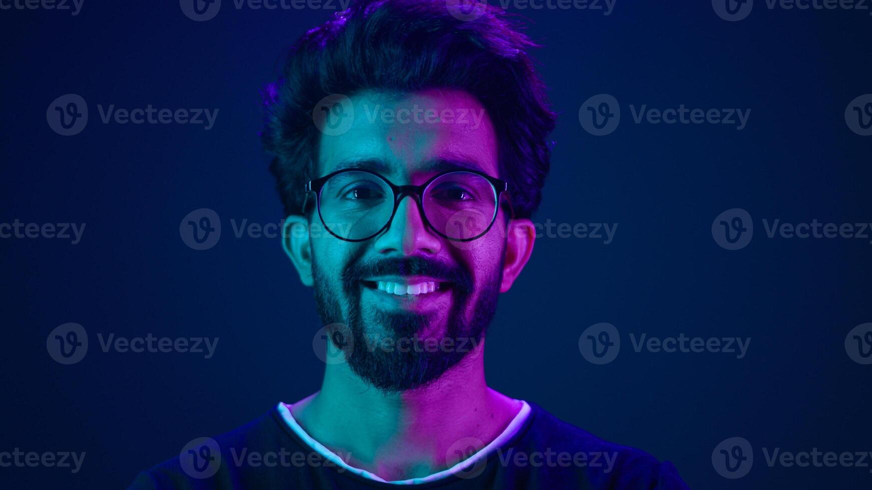 Portrait Indian man Muslim guy developer coding worker smile computer internet technology hacker Arabian male in glasses smiling neon blue ultraviolet studio background high-tech future cyberspace photo