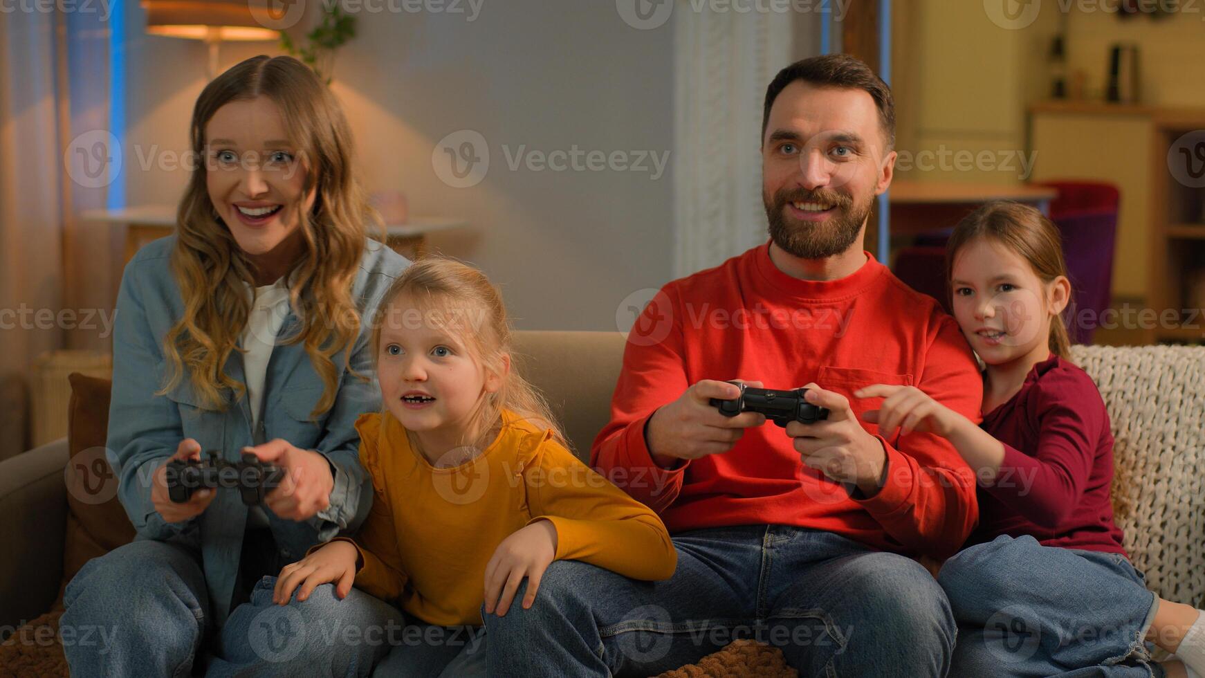 Funny children parents Caucasian happy family play game online at home weekend mom dad kids little girls daughters addicted playing console with joysticks have fun gaming entertainment together photo