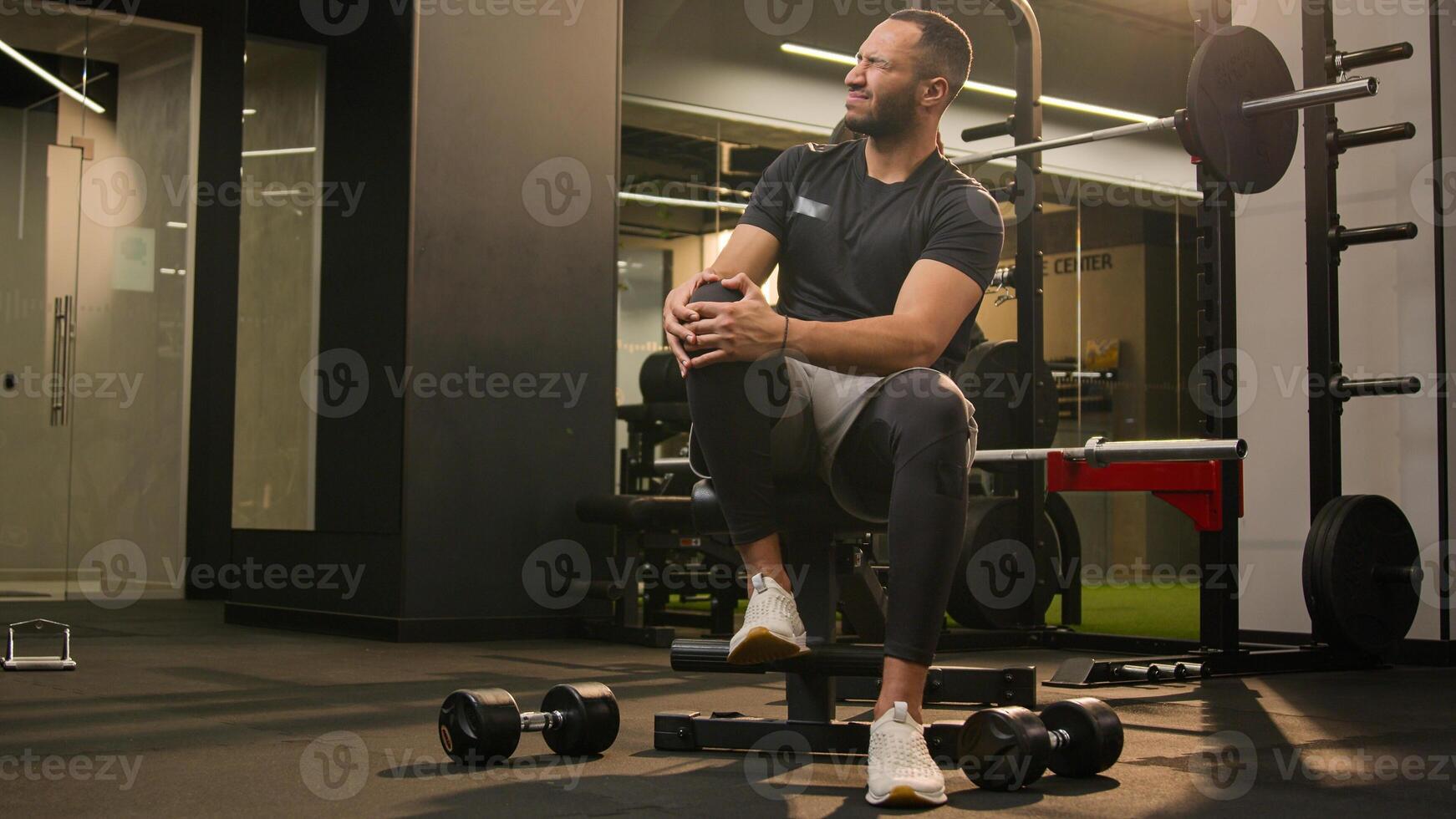 African American unwell man sad suffering with knee pain in sport club workout trauma sporty man muscle ache sportsman athlete male injuring leg in training painful injury in fitness gym ache damage photo