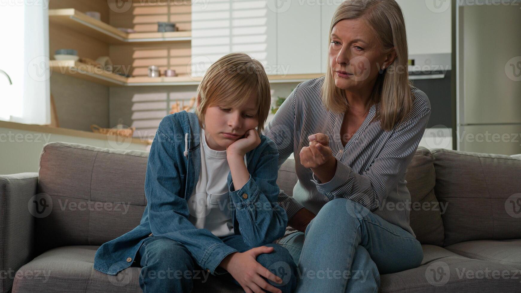 Strict angry elderly senior Caucasian woman grandmother punishing disobedient lazy offended grandson at home scolding grandchild kid boy due to bad behavior discipline family conflict explaining rules photo