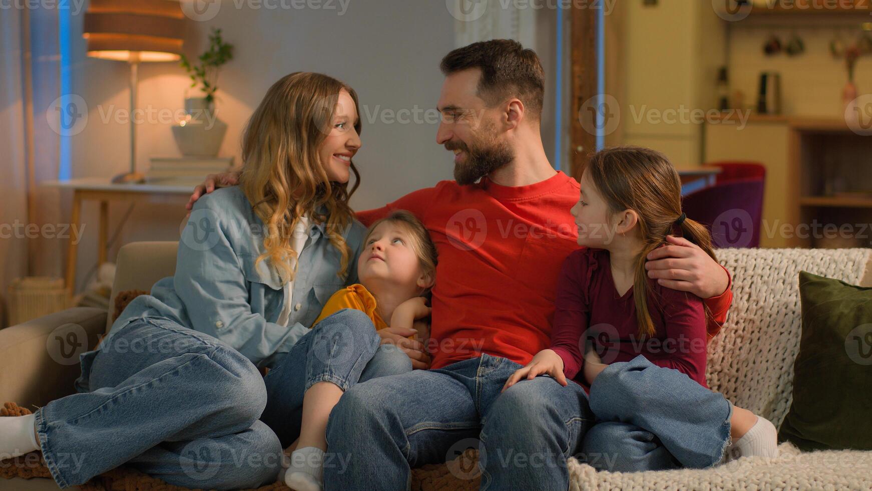 Happy friendly bonding affectionate family Caucasian parents children little girls daughters siblings on sofa evening weekend cheerful mother father kids hugging smile laugh relax home mortgage loan photo