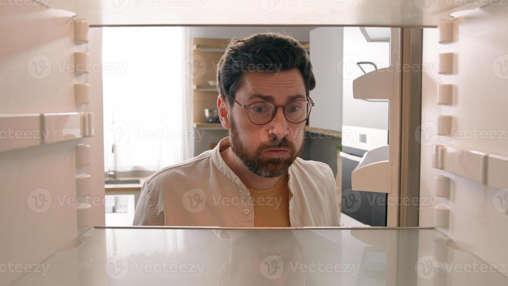 Point of view POV inside refrigerator Caucasian hungry man male homeowner householder unemployed guy bachelor open fridge at kitchen unhappy sad with empty shelves have noting to eat food delivery photo