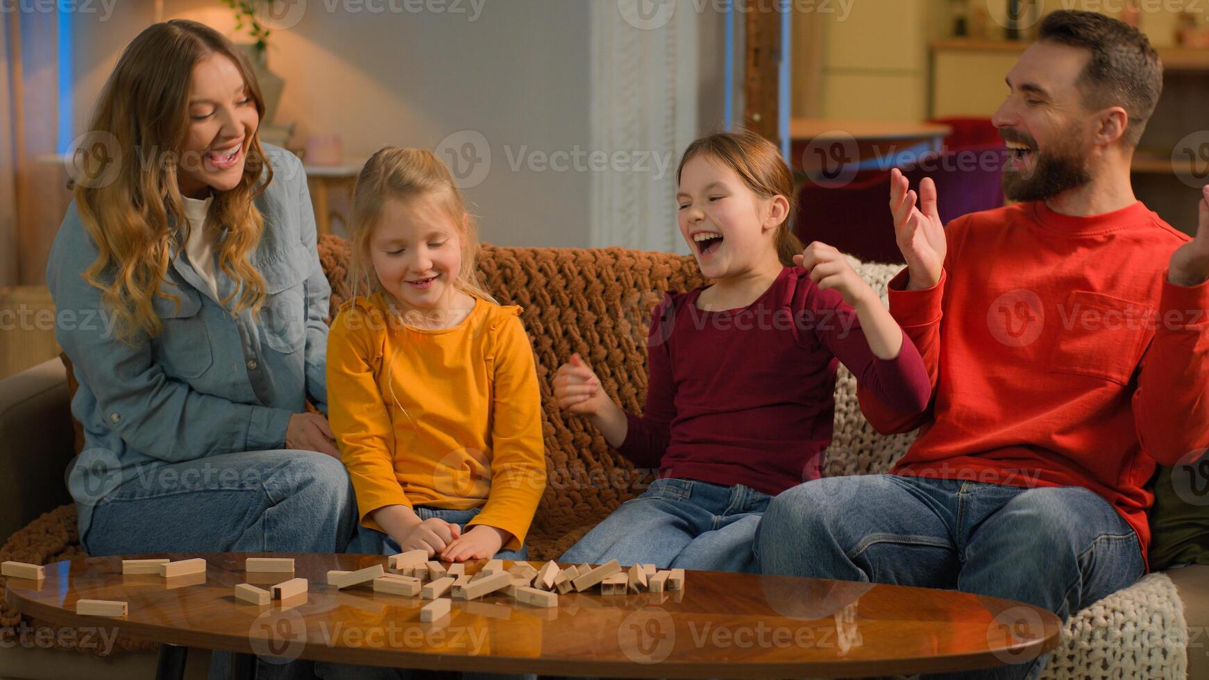 Happy family Caucasian mother father play with kids build tower wooden blocks playful little girls preschool daughters siblings playing game at home parents learning children custody school education photo