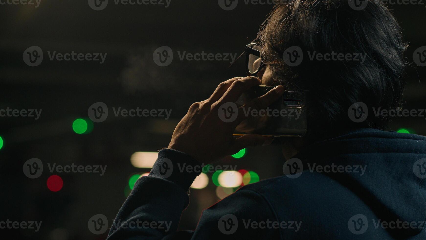 Back view from behind male in glasses at parking lot dark underground shelter man guy businessman talk phone speaking business call talking mobile conversation distant communication with smartphone photo