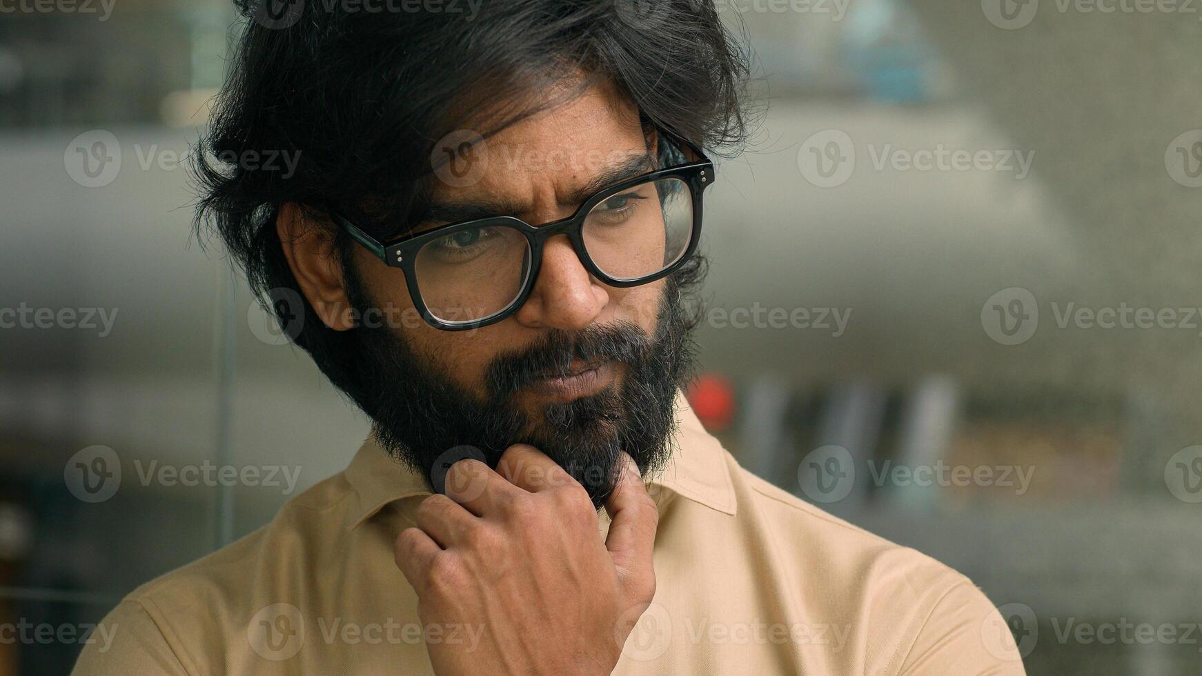Thoughtful worried Arabian businessman thinking of future business challenges financial crisis. Doubtful serious pensive Indian bearded man in glasses entrepreneur lost in thoughts think about problem photo