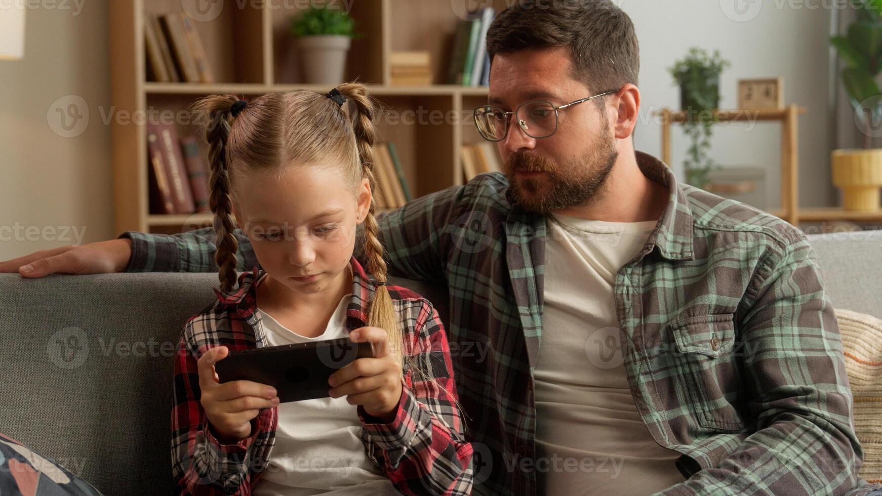 Worried upset Caucasian dad man male daddy touching speak little girl child daughter family problem at home bad behavior kid ignore father guy playing online game mobile phone device gadget addiction photo