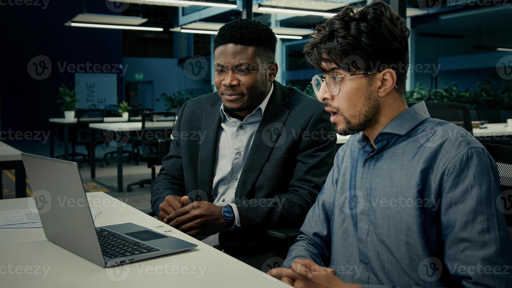 Two businessmen business partners office African American man client talk with Indian businessman colleague diverse ethnic multiracial men laughing having fun discuss online project on computer laptop photo