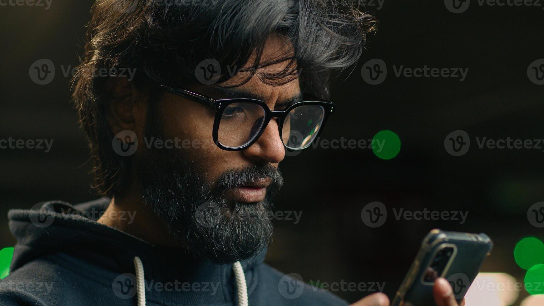 Close up Indian man at dark parking lot shocked stressed annoyed disappointed upset with mobile phone message bad news Arabian male guy stress by failure business lost with smartphone at underground photo