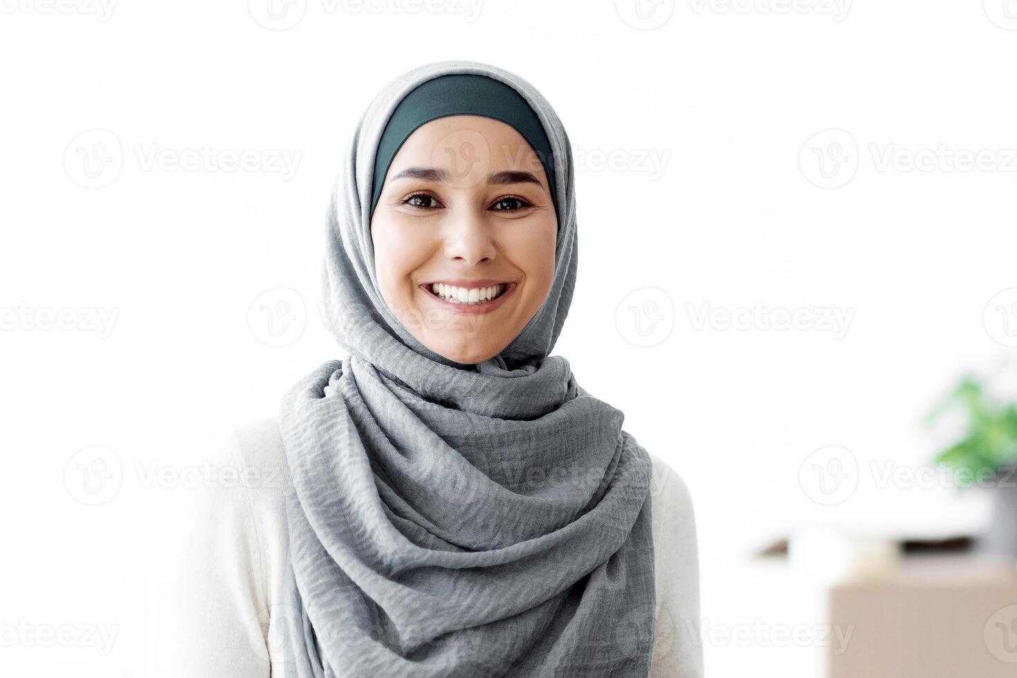 Happy muslim family husband and wife holding moving supplies in their new apartment, copy space. Smiling arab couple with paper boxes with belongings standing in their new house photo