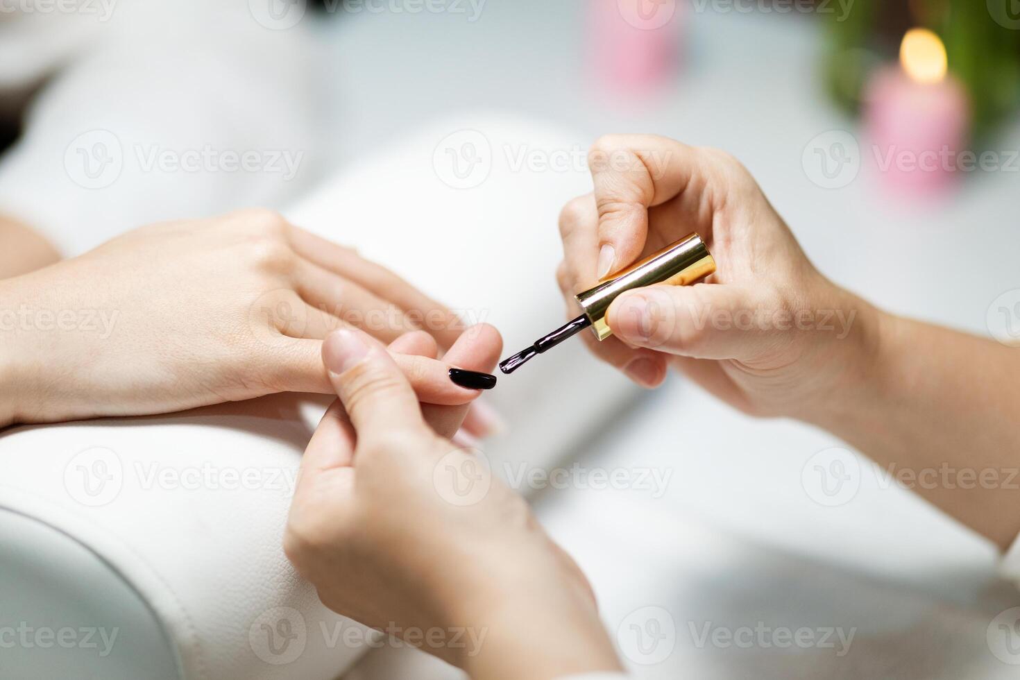 A woman enjoys a pampering session at a fashion-forward salon, where a nail technician carefully applies a nail polish to her hand. The atmosphere is serene and inviting. photo