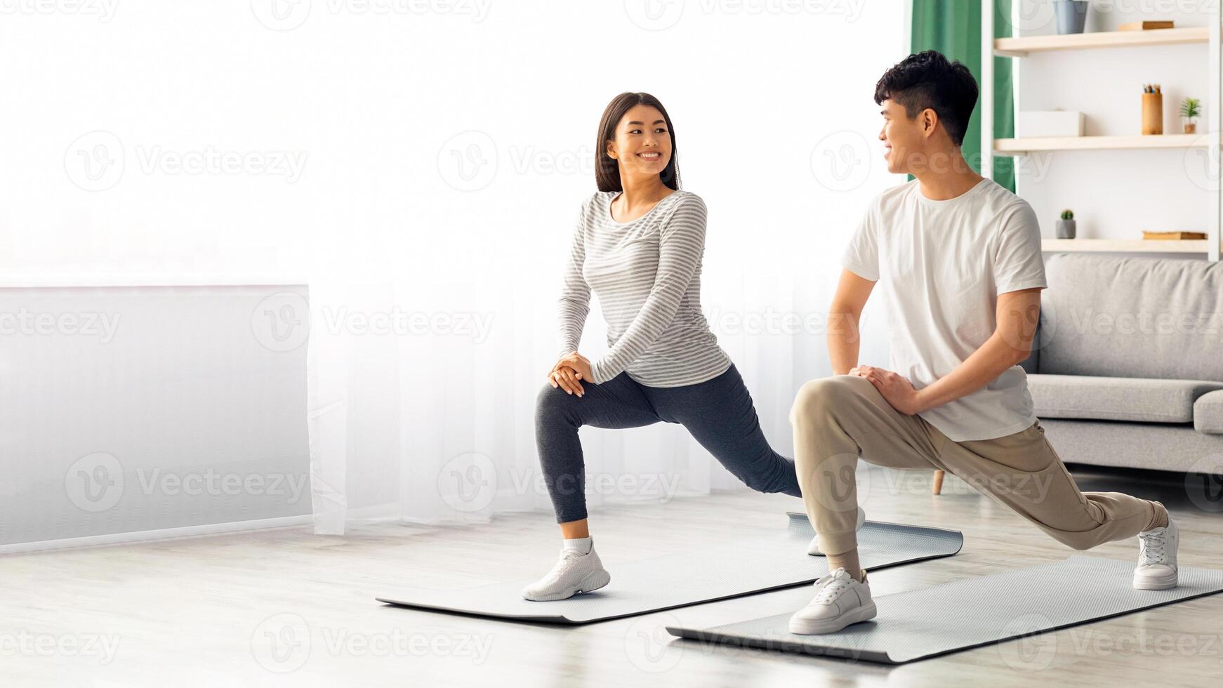 Happy asian young couple exercising together at home, positive korean man and woman in sportswear standing on fitness mat, stratching and having conversation, copy space. Healthy lifestyle concept photo