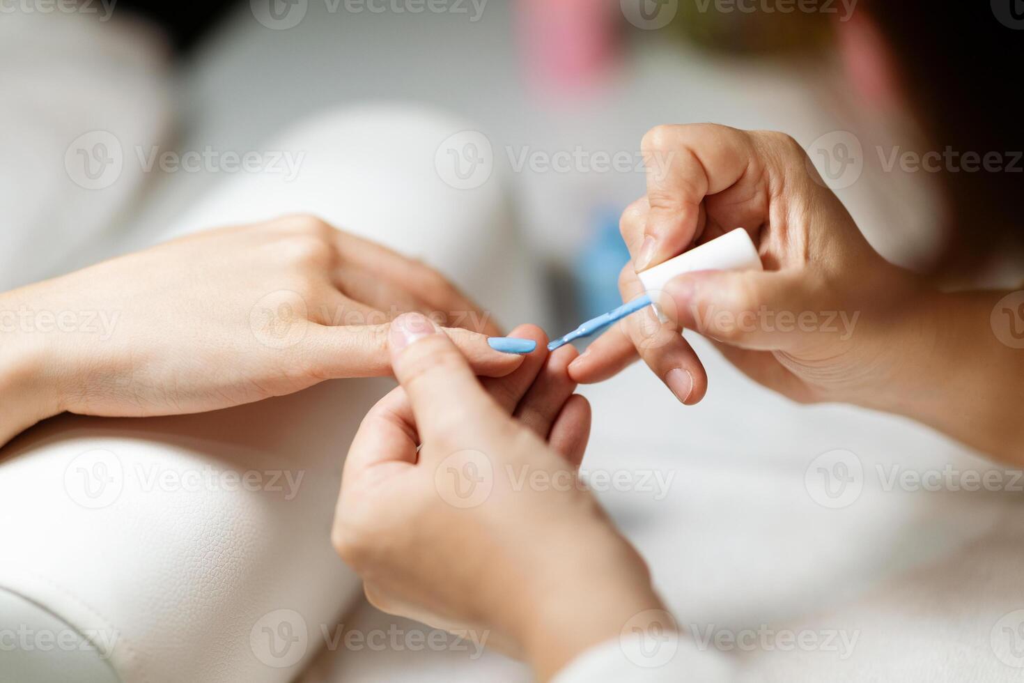 A skilled technician applies a vibrant nail polish while pampering a woman at a stylish salon. The atmosphere is relaxing, showcasing the latest nail trends and techniques. photo