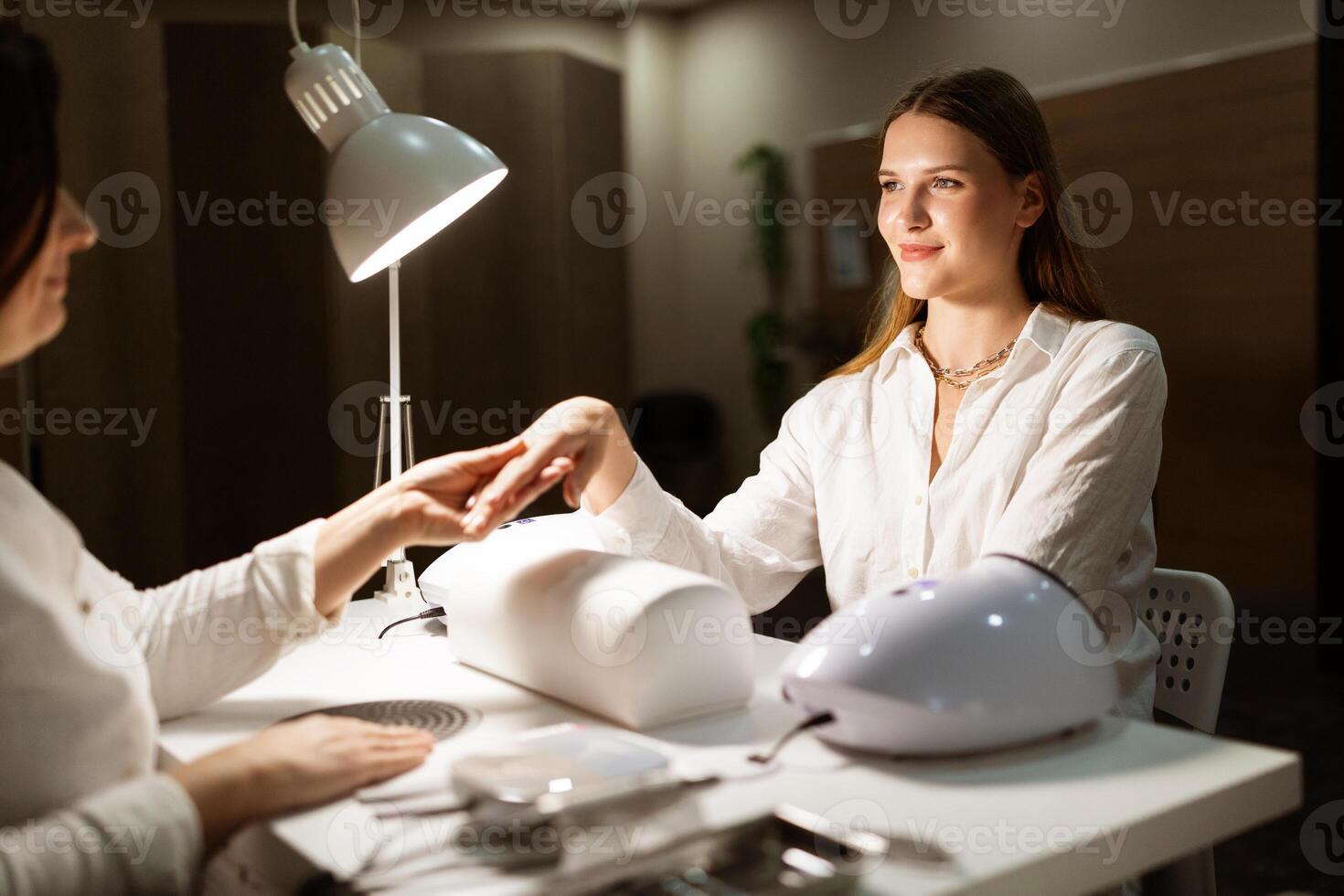 A woman is receiving a manicure at a modern salon, with focus on her hands and nails. The salon has a relaxing atmosphere, perfect for a beauty treatment. photo