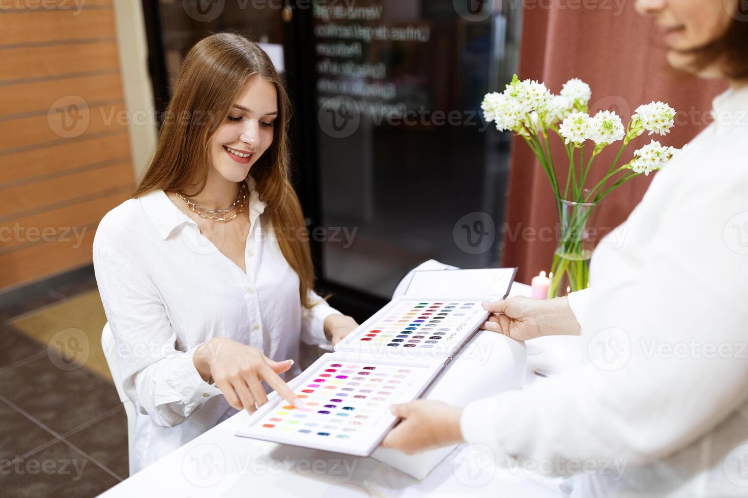 Ladies are pampering themselves at a busy salon, selecting from a wide range of nail colors. The atmosphere is relaxed, with attention to detail in the manicuring process. photo