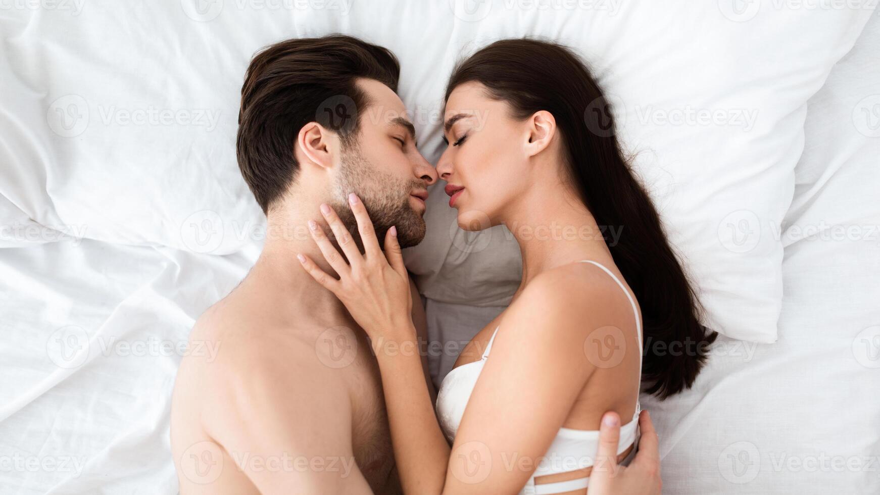Top View Of Loving Couple Kissing Making Love Lying In Bed Indoors. Boyfriend And Girlfriend Making Sex Enjoying Intimacy Foreplay And Sensual Pleasure At Home. Shot Of Passionate Lovers photo
