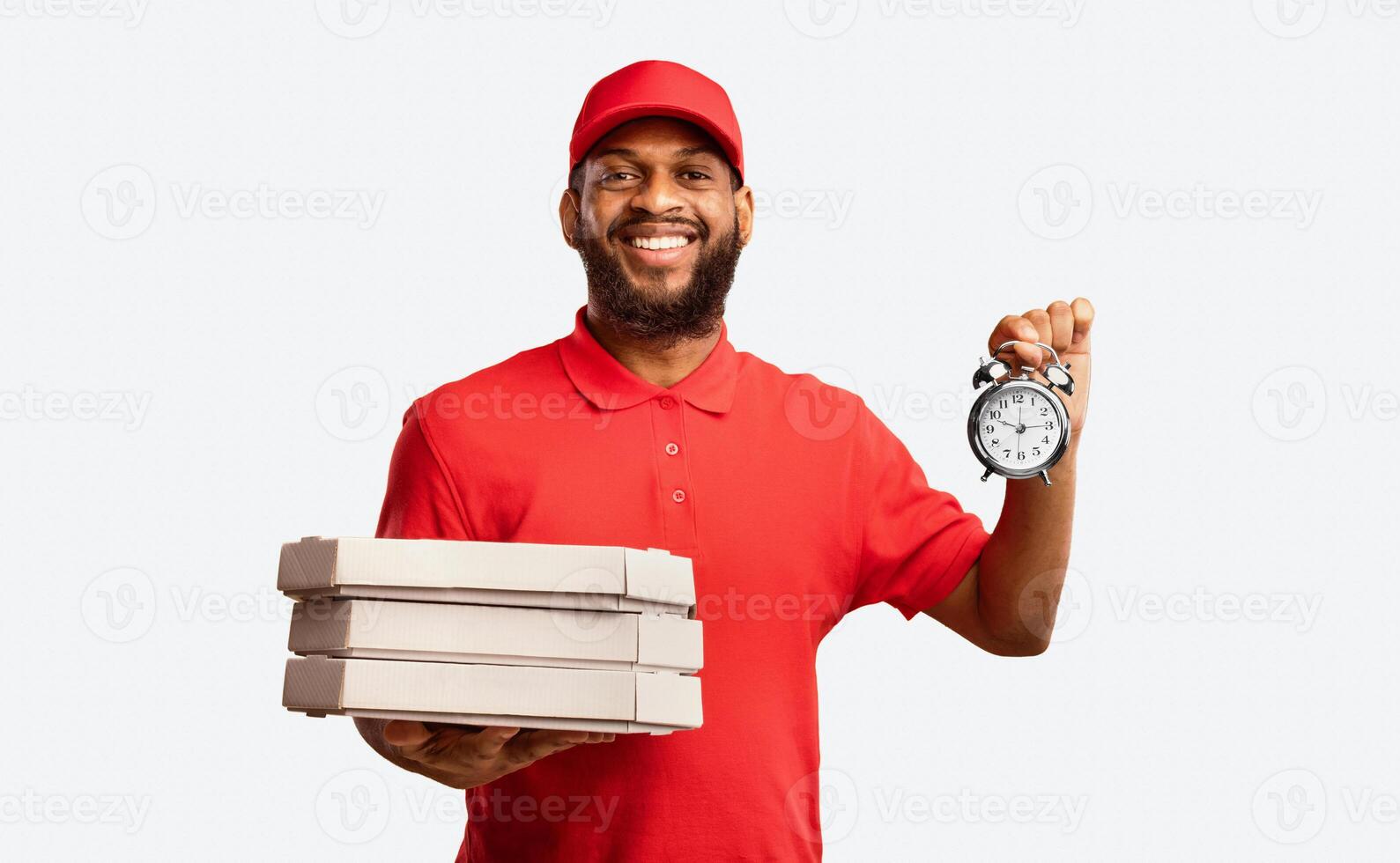 Pizzeria Courier Delivering Pizza On-Time Holding Boxes And Clock Smiling To Camera Posing Over Yellow Studio Background. photo