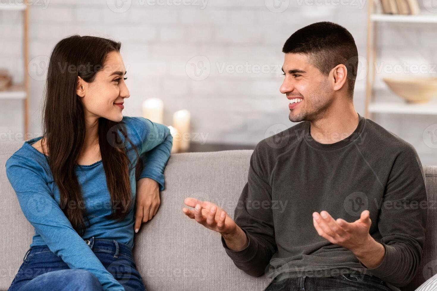 Beautiful couple talking, sitting on couch at home, have a nice conversation at their cozy apartment photo