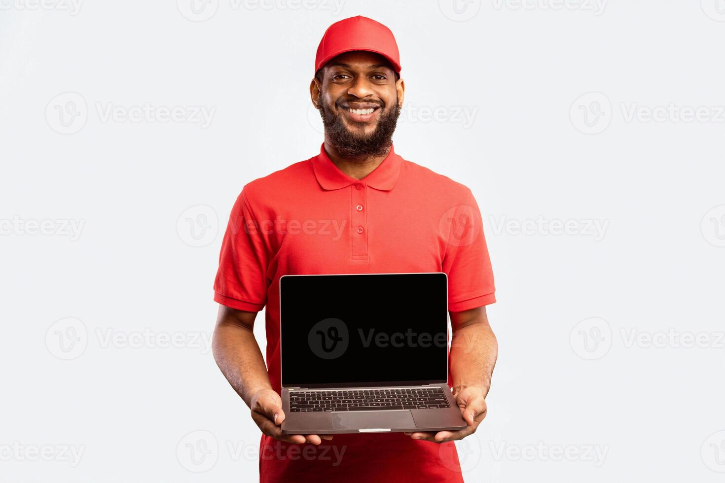 Delivery Man Holding Laptop With Empty Screen Standing In Studio On Yellow Background. Mockup. Courier And Shipping Service photo